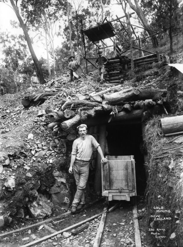 image historique en noir et blanc d'un homme debout devant une mine d'or de la Nouvelle-Angleterre